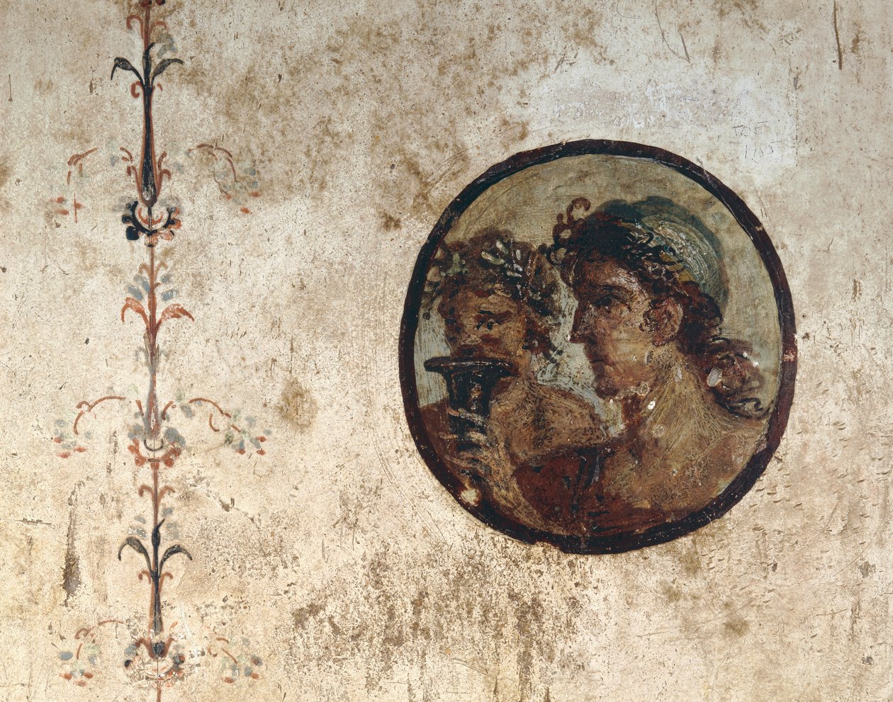 Innenraum eines Zimmers mit Wandfresken aus der römischen Zeit, Stil III, im Haus von Corieo Tiburtino in Pompeji: Teil einer Rebe und ein Tondo mit zwei männlichen Köpfen von Unknown