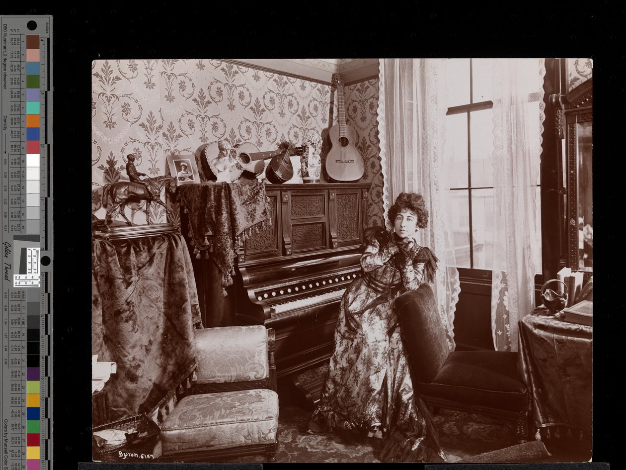 Anita Chartres sitzt an einem Pianola, ca. 1898 von Byron Company