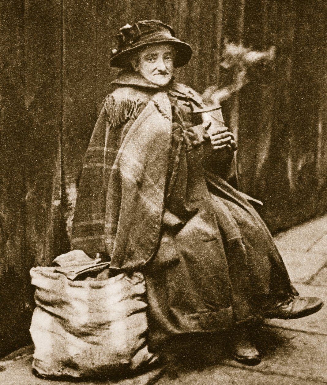 Eine Straßenfrau trinkt Tee aus einer typischen East End Bierdose von English Photographer