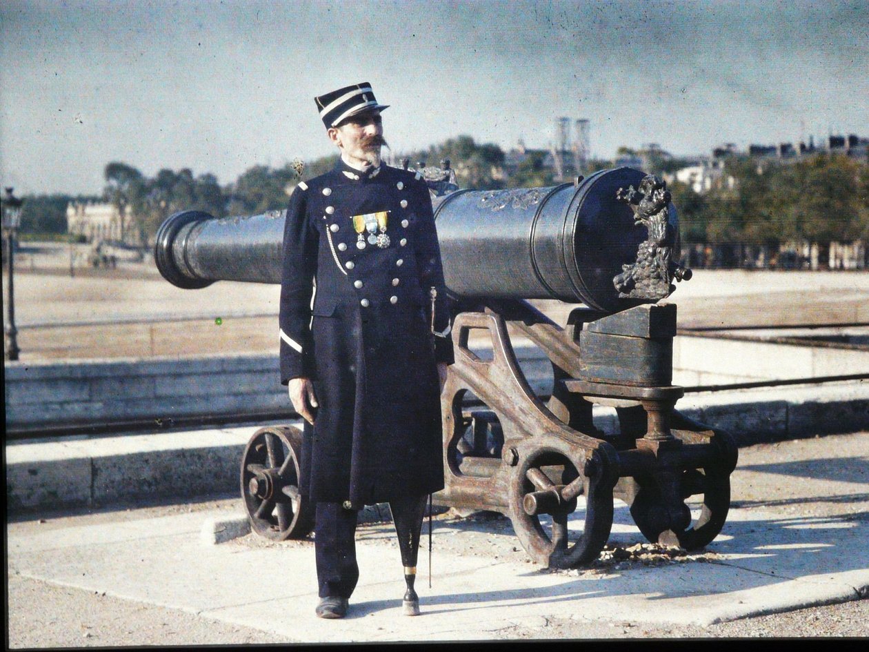Ein Soldat in Uniform mit drei Medaillen steht neben einer Kanone in Paris von Jules Gervais Courtellemont