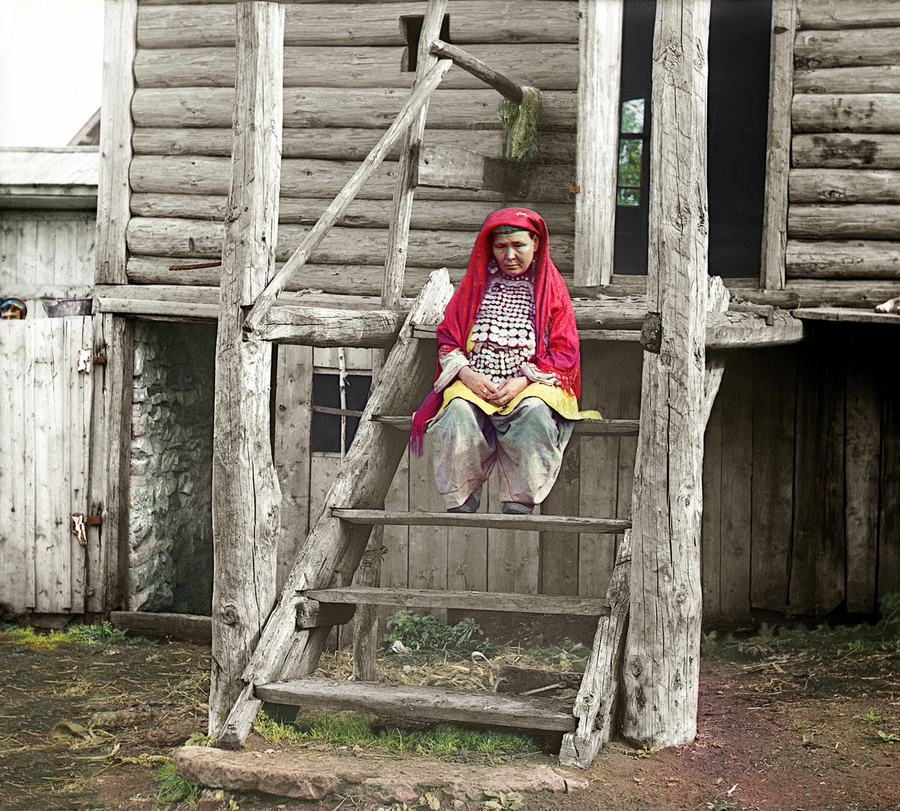 Baschkirische Frau in Volkstracht, sitzend auf der Treppe ihres Holzhauses, Uralgebirge, Russisches Reich, 1910 von Sergey Prokudin Gorsky