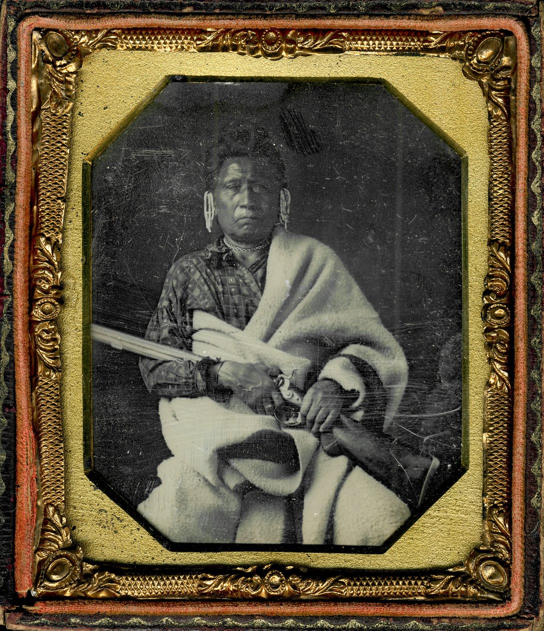 Porträt von Nacheninga [No Heart of Fear], Iowa. Nacheninga hält eine Waffe in den Händen und ist in eine dicke Decke gehüllt. von Thomas M. Easterly