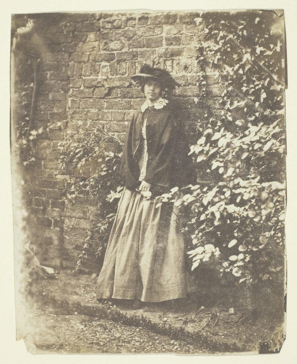 Mrs. Craik lehnt an Wand und Büschen von Unknown